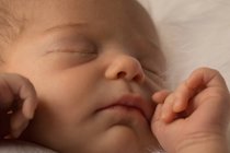 Close-up of face of newborn baby sleeping on baby bed. — Stock Photo