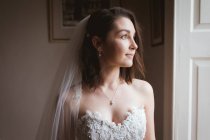 Smiling bride looking out of the window at home — Stock Photo