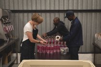 Trabalhadores que embalam garrafas de gin na fábrica — Fotografia de Stock