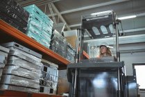 Женщина-работница за рулем погрузчика на складе — стоковое фото