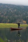 Чоловік в каное кидає рибальську лінію в річці біля пасовища — стокове фото