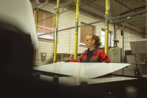 Женщина-работница проверяет стеклянный лист на заводе — стоковое фото