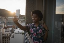 Mujer tomando selfie con teléfono móvil en balcón . - foto de stock