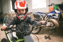 Дитина готується до їзди на велосипеді в гаражі — стокове фото