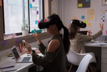 Duas designers femininas usando headset de realidade virtual no escritório . — Fotografia de Stock