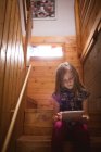 Menina bonito usando tablet na escada em casa — Fotografia de Stock