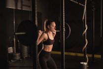 Jeune femme levant avec haltère dans la salle de gym — Photo de stock