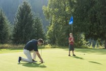 Батько і син грають в гольф на трасі — стокове фото