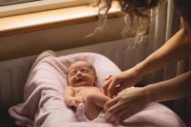 Mother dressing newborn baby girl at bed. — Stock Photo
