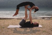 Sportliches Paar praktiziert an einem sonnigen Tag Acroyoga in Küstennähe — Stockfoto
