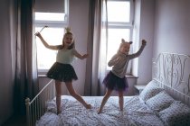 Девушки в костюмах танцуют на кровати в спальне — стоковое фото