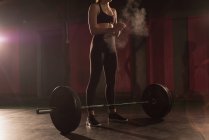 Woman rubbing powder on hand before barbell workout in gym — Stock Photo