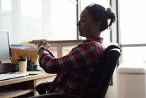 Executivo feminino usando smartwatch no escritório — Fotografia de Stock