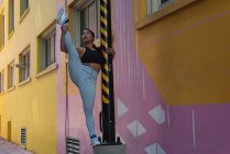 Female street dancer on the pole in the city street — Stock Photo