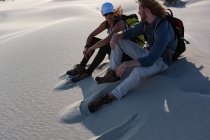 Casal relaxante na areia no deserto em um dia ensolarado — Fotografia de Stock