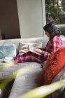 Femme lisant un livre dans le salon à la maison — Photo de stock