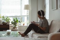 Donna che ascolta musica mentre scrive nel taccuino a casa — Foto stock