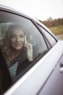 Femme d'affaires souriante parlant au téléphone sur le siège arrière de la voiture — Photo de stock