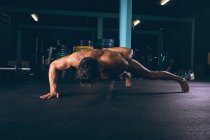 Решительный мускулистый человек делает отжимания в фитнес-студии — стоковое фото