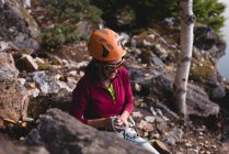 Escursionista femminile che si prepara a scalare la montagna rocciosa vicino al lago — Foto stock