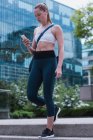 Молода спортивна жінка використовує мобільний телефон на вулиці — стокове фото