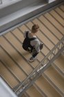Высокий угол обзора студента колледжа, идущего с ноутбуком на лестнице — стоковое фото