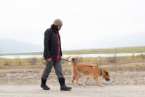 Homem e seu cão de estimação caminhando no caminho vazio — Fotografia de Stock