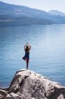 Жінка заняттях йогою на скелі біля моря — стокове фото