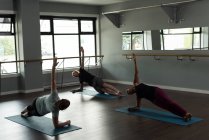 Trainer unterstützt Menschen beim Yoga im Fitnessstudio. — Stockfoto