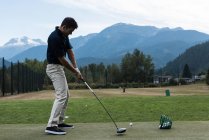 Hombre realizando un swing de golf en el campo de golf - foto de stock