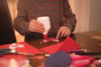 Sección media del niño preparando la tarjeta de San Valentín en casa - foto de stock
