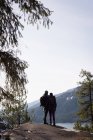 Visão traseira do casal caminhante em pé na rocha perto da ribeira em um dia ensolarado — Fotografia de Stock