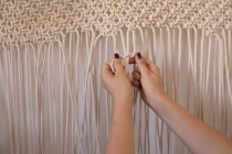 Frau knotet Schnüre gegen Wand — Stockfoto