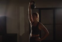 Женщина делает упражнения с гирями в тренажерном зале — стоковое фото