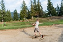 Хлопчик робить постріл у поле для гольфу — стокове фото