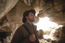 Wanderer inspiziert an einem sonnigen Tag Felsen in einer Höhle — Stockfoto
