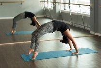 Woman practicing yoga on exercise mat in fitness studio. — Stock Photo