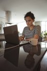 Mulher trabalhando no laptop enquanto toma café em casa — Fotografia de Stock