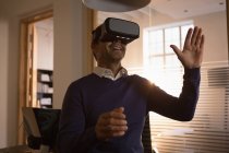 Empresário sorridente usando headset de realidade virtual no escritório . — Fotografia de Stock