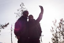 Caminante pareja tomando selfie con teléfono móvil en un día soleado - foto de stock