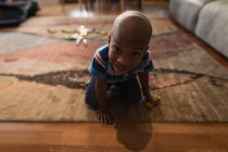 Porträt eines Jungen, der es sich auf Teppich im heimischen Wohnzimmer gemütlich macht. — Stockfoto