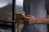 Чоловік використовує мобільний телефон на балконі вдома — стокове фото