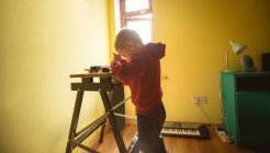 Хлопчик використовує інструмент на дерев'яній дошці вдома — стокове фото