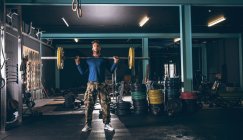 Muscular man exercising with barbell in the fitness studio — Stock Photo