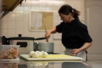 Balls of dough on a chopping board while chef cooking in background — Stock Photo