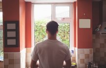 Вид сзади человека, стоящего в кухонном интерьере . — стоковое фото