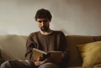 Homme lecture livre dans le salon à la maison — Photo de stock