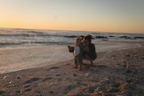 Mãe e filho soprando bolha com varinha de bolha na praia durante o pôr do sol — Fotografia de Stock