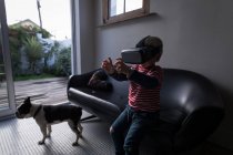 Garçon utilisant casque de réalité virtuelle dans le salon à la maison . — Photo de stock