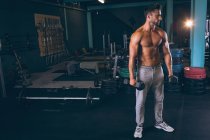 М'язистий чоловік займається з гантелями в фітнес-студії — стокове фото
